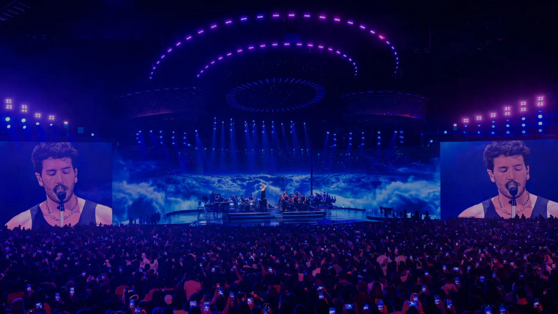 A stadium-scale live production surrounded by a large concert audience.
